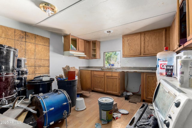 kitchen featuring light wood finished floors, light countertops, brown cabinetry, and open shelves