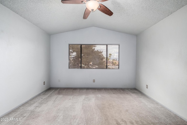 carpeted spare room featuring ceiling fan, vaulted ceiling, and a textured ceiling