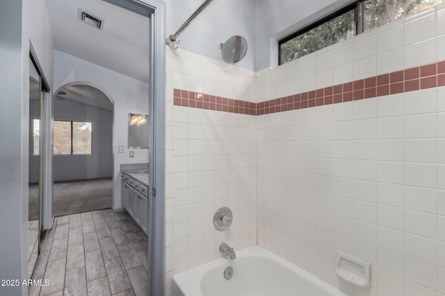 bathroom with bathtub / shower combination, vanity, and visible vents