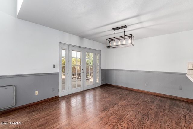 empty room with wood finished floors, baseboards, and french doors