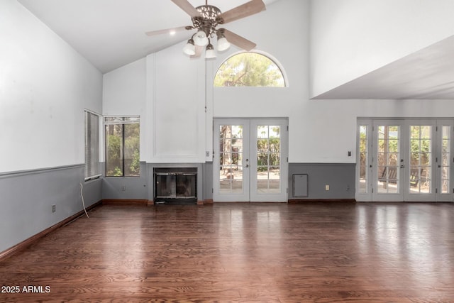 unfurnished living room with wood finished floors, high vaulted ceiling, french doors, and a healthy amount of sunlight