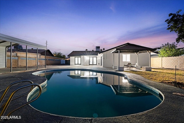 3506 W Yucca St, Phoenix, AZ 85029 - pool at dusk with french doors, a patio, and a fenced backyard