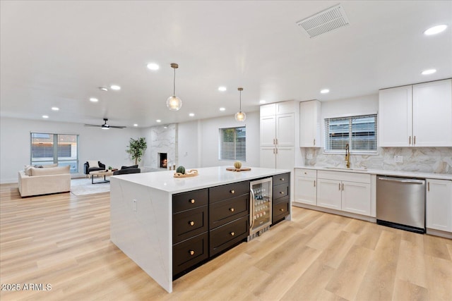 3506 W Yucca St, Phoenix, AZ 85029 - kitchen with stainless steel dishwasher, wine cooler, white cabinetry, a fireplace, and light countertops