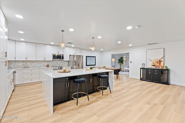 3506 W Yucca St, Phoenix, AZ 85029 - kitchen featuring stainless steel appliances, a spacious island, light countertops, white cabinets, and light wood-style flooring