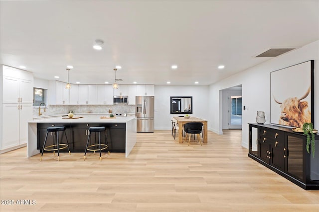 3506 W Yucca St, Phoenix, AZ 85029 - kitchen with stainless steel appliances, light countertops, white cabinets, a spacious island, and a kitchen bar