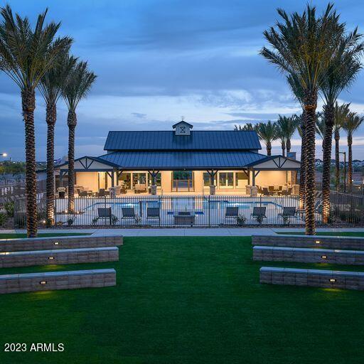 back house at dusk with a fenced in pool, a patio area, and a lawn