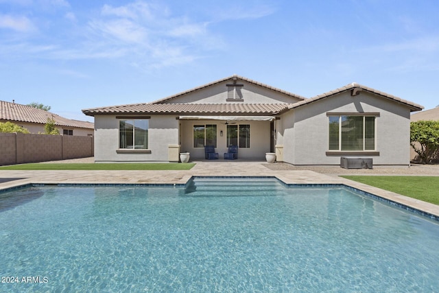 rear view of property with ceiling fan, a patio area, and a fenced in pool