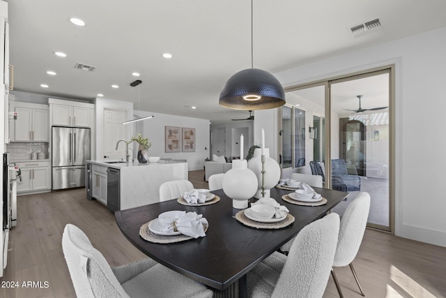 dining space with hardwood / wood-style floors, ceiling fan, and sink