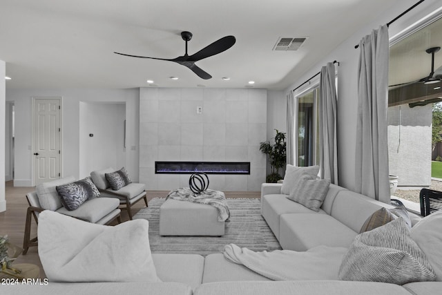 living room featuring ceiling fan, a tile fireplace, and light hardwood / wood-style flooring