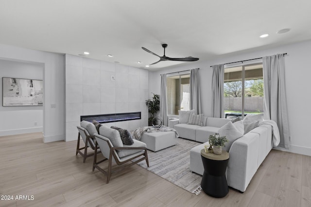 living room featuring ceiling fan, a fireplace, and light wood-type flooring