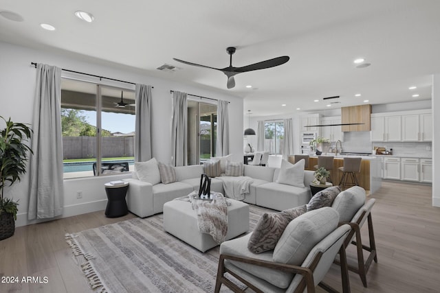 living room featuring ceiling fan, light hardwood / wood-style floors, and sink