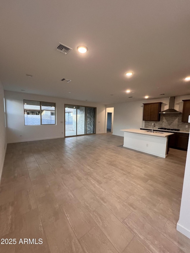 unfurnished living room featuring recessed lighting, a sink, visible vents, and baseboards