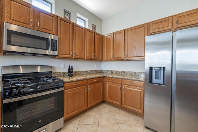 kitchen featuring light stone countertops, stainless steel appliances, and light tile patterned flooring