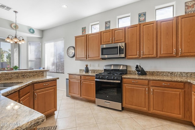 kitchen with plenty of natural light, gas stove, hanging light fixtures, and light tile patterned floors