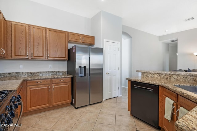 kitchen with light tile patterned flooring, light stone counters, and black appliances