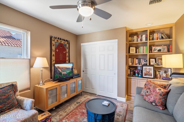 living area with visible vents and ceiling fan