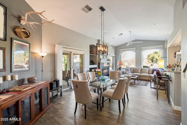 dining room with dark wood-type flooring, a warm lit fireplace, visible vents, and a healthy amount of sunlight