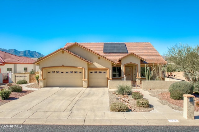 mediterranean / spanish home with a mountain view, a garage, and solar panels