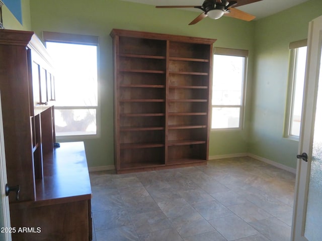 interior space with baseboards and a ceiling fan