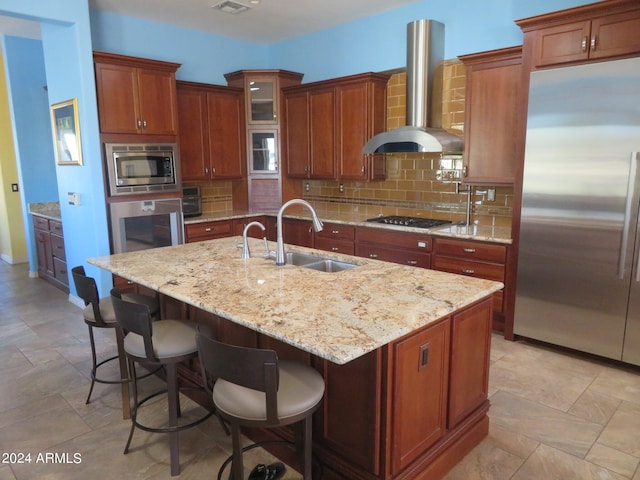 kitchen featuring decorative backsplash, a center island with sink, appliances with stainless steel finishes, extractor fan, and sink