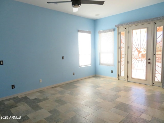 unfurnished room featuring baseboards, ceiling fan, and stone finish floor