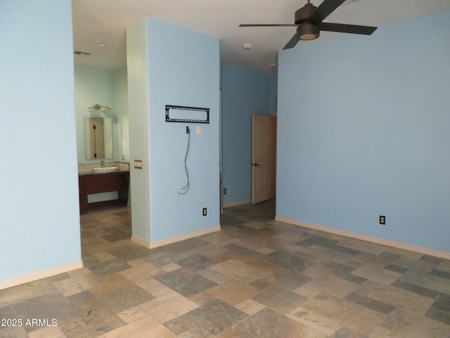 spare room with baseboards, a sink, ceiling fan, and stone finish floor