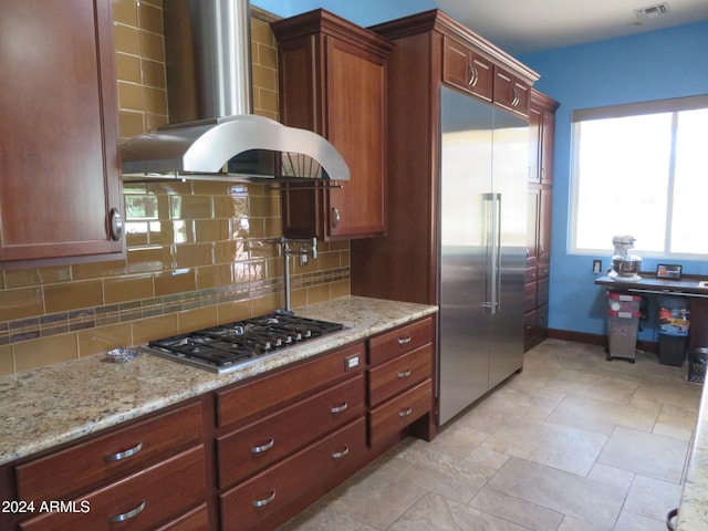 kitchen featuring light stone countertops, island exhaust hood, decorative backsplash, and stainless steel appliances