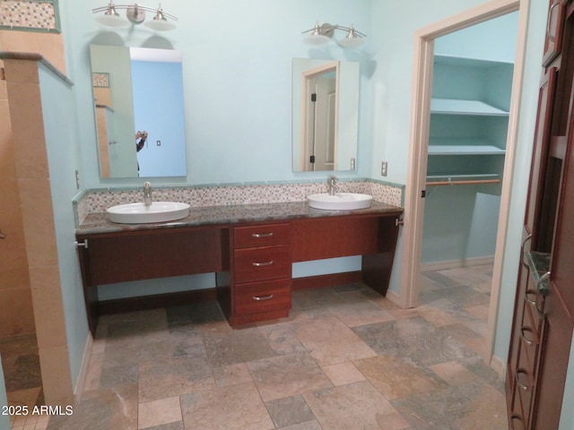 bathroom featuring double vanity, a sink, and stone finish floor