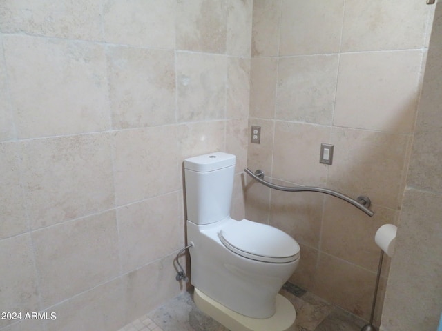 bathroom featuring toilet and tile walls