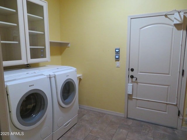 clothes washing area featuring laundry area, stone finish flooring, baseboards, and independent washer and dryer
