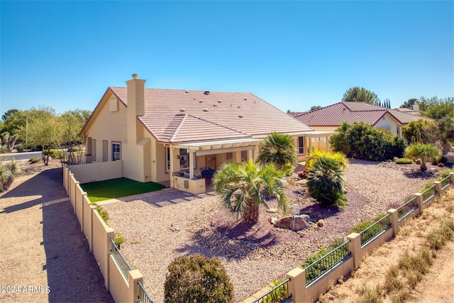 view of front of home with a fenced backyard, stucco siding, a tiled roof, and a chimney