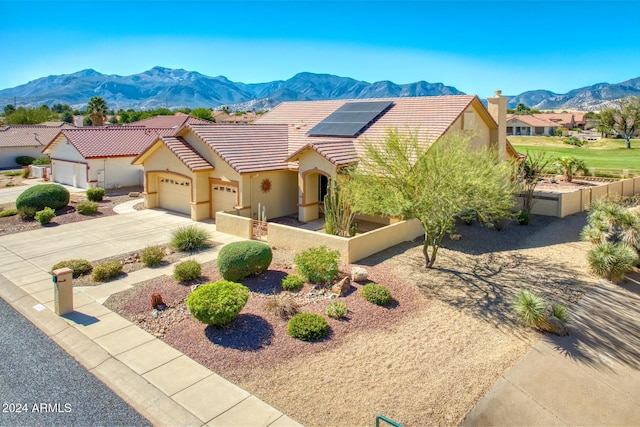view of front facade featuring an attached garage, fence private yard, a mountain view, and stucco siding