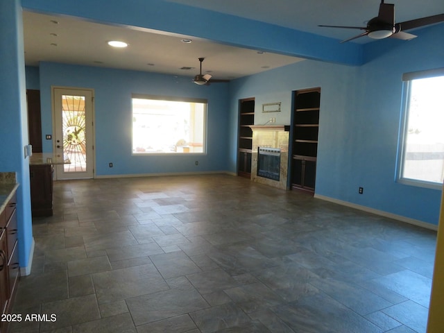 unfurnished living room with baseboards, ceiling fan, recessed lighting, built in shelves, and a tiled fireplace