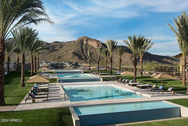 view of swimming pool with a patio, a mountain view, a lawn, and a jacuzzi