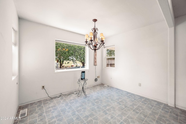 unfurnished room featuring a chandelier