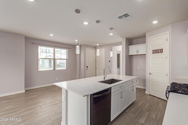 kitchen featuring pendant lighting, white cabinetry, a kitchen island with sink, and sink