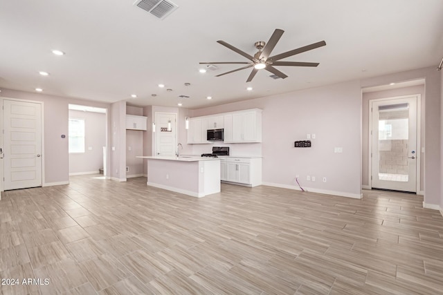 kitchen featuring white cabinets, black range, sink, ceiling fan, and an island with sink