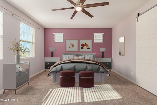 bedroom featuring a barn door, ceiling fan, and light colored carpet