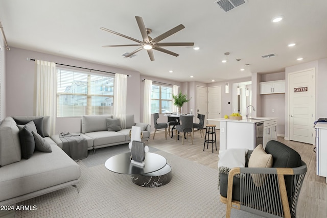 living room with light hardwood / wood-style flooring, ceiling fan, and sink