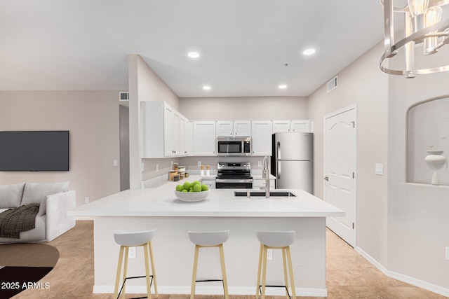 kitchen featuring a breakfast bar area, white cabinetry, sink, and appliances with stainless steel finishes