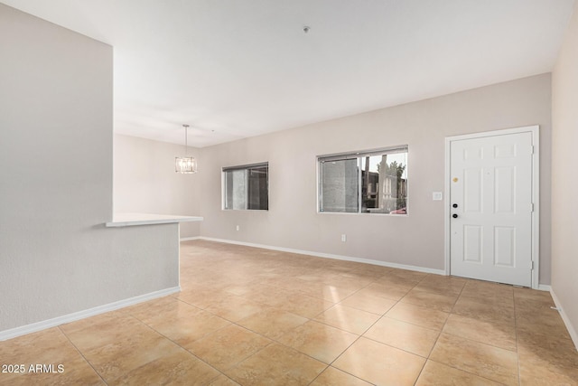 tiled spare room with a notable chandelier