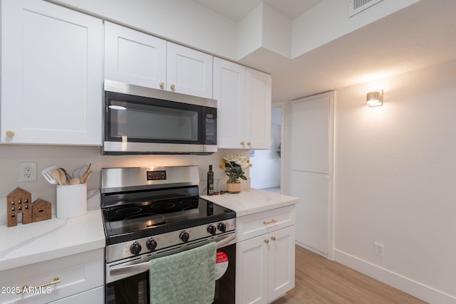 909 S Acapulco Ln Unit A, Tempe, AZ 85281 - kitchen featuring appliances with stainless steel finishes, light wood-style flooring, white cabinetry, baseboards, and light stone countertops