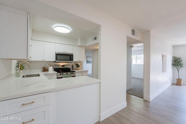 909 S Acapulco Ln Unit A, Tempe, AZ 85281 - kitchen with appliances with stainless steel finishes, a sink, light stone countertops, light wood-style floors, and white cabinets