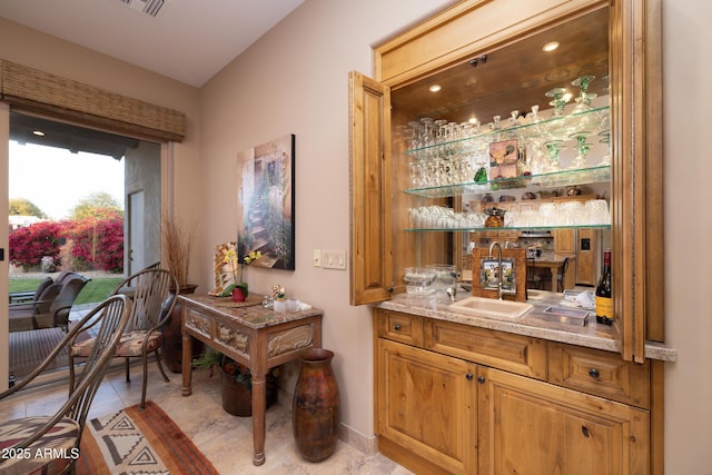 bar featuring light stone counters and sink