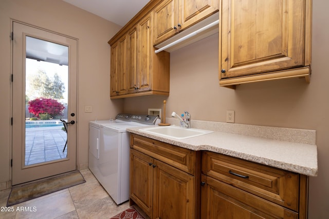 clothes washing area featuring cabinets, sink, light tile patterned floors, and washing machine and clothes dryer