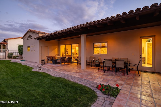 back house at dusk with a yard and a patio area