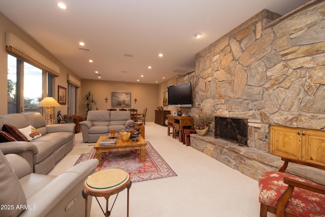 carpeted living room with a stone fireplace