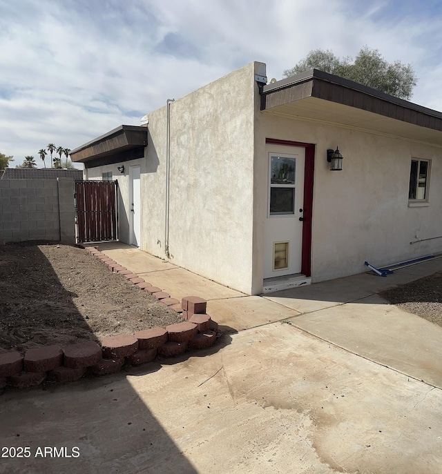 back of house featuring a patio area, a gate, fence, and stucco siding