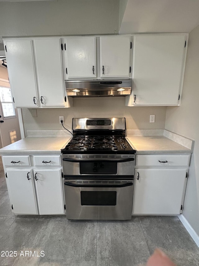 kitchen with light countertops, white cabinets, double oven range, and under cabinet range hood