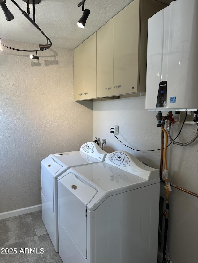 laundry area with a textured wall, washing machine and dryer, tankless water heater, and cabinet space